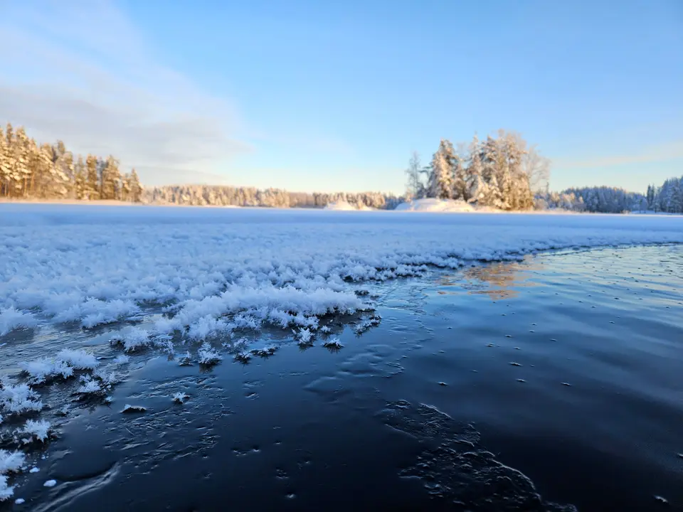Suuria jääkukkia avoimen avannon reunalla auringonpaisteessa